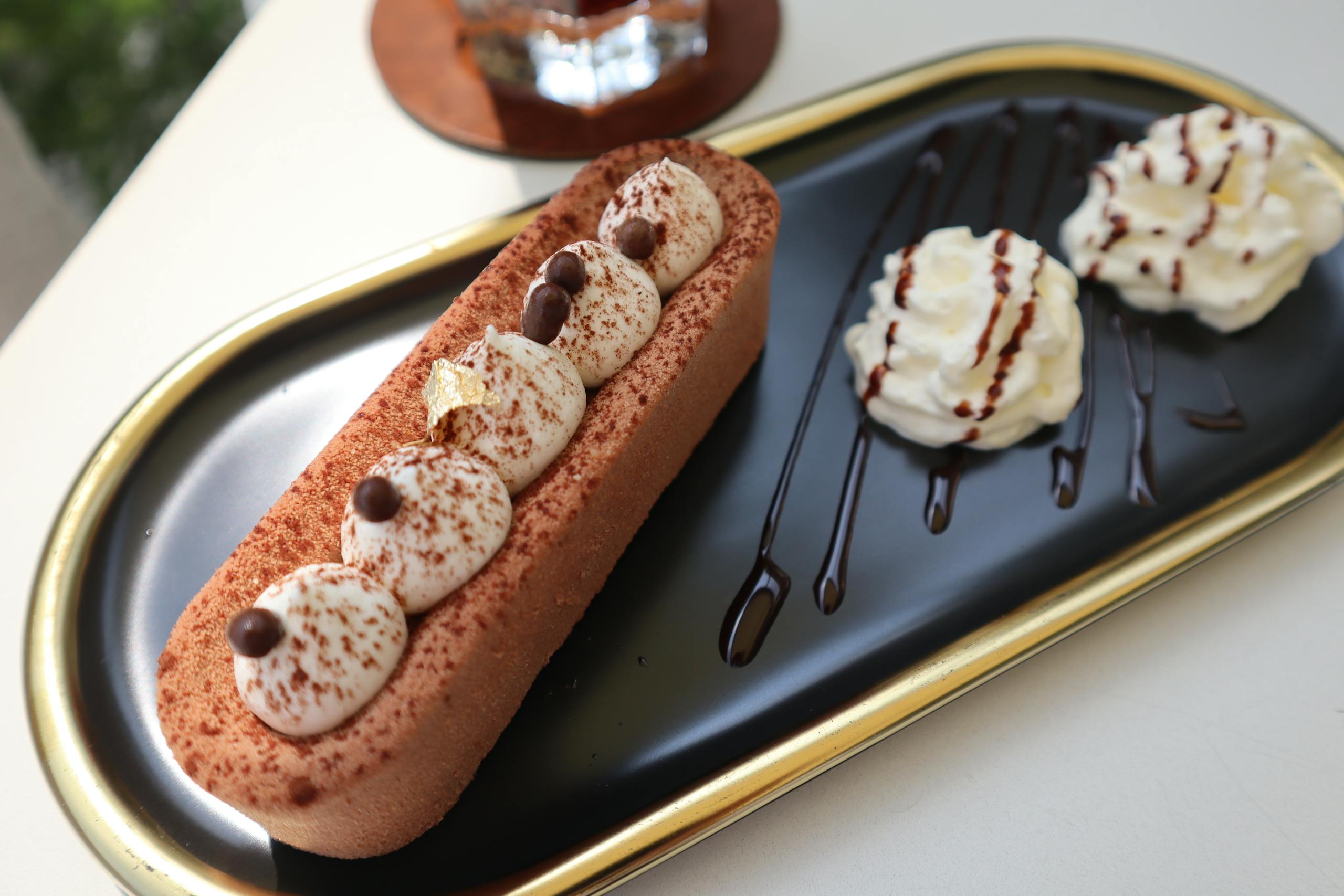 Delicious chocolate dessert garnished with whipped cream and chocolate drizzle on a stylish platter.